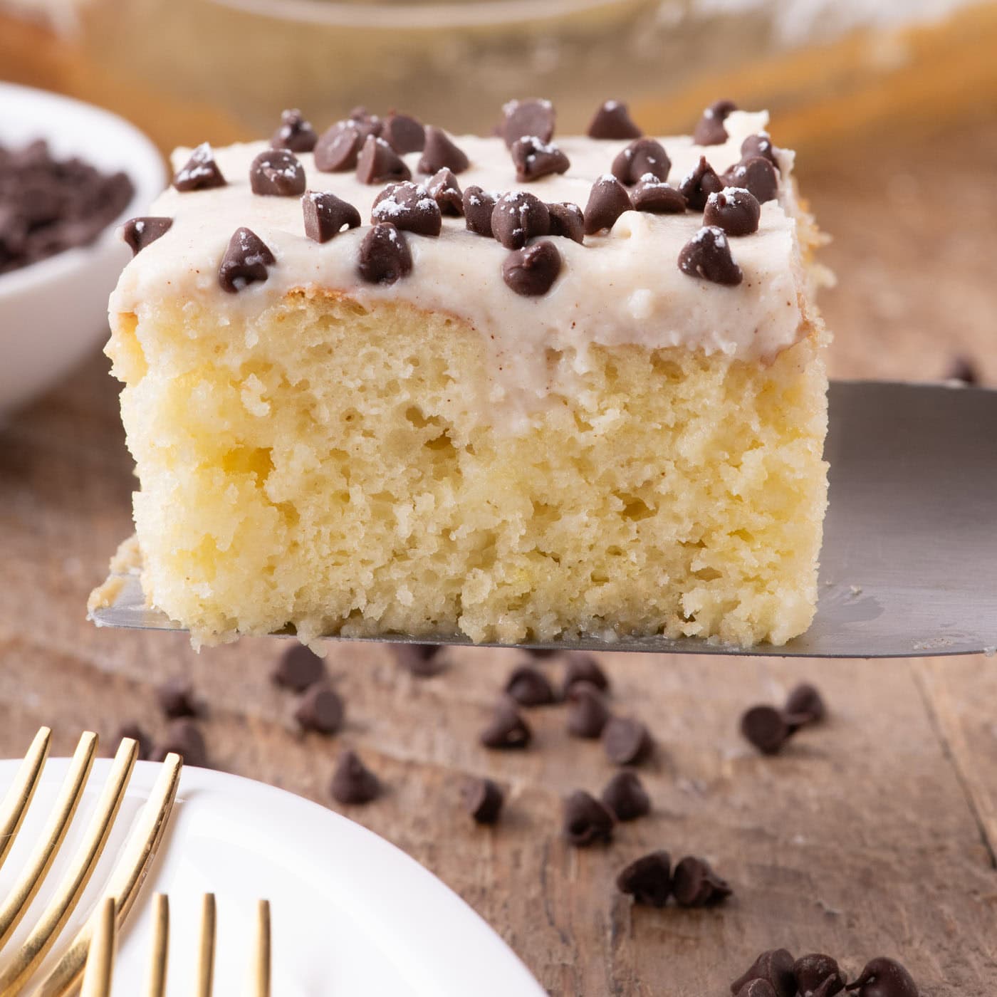 Close up photo of a slice of Cannoli Poke Cake on a spatula