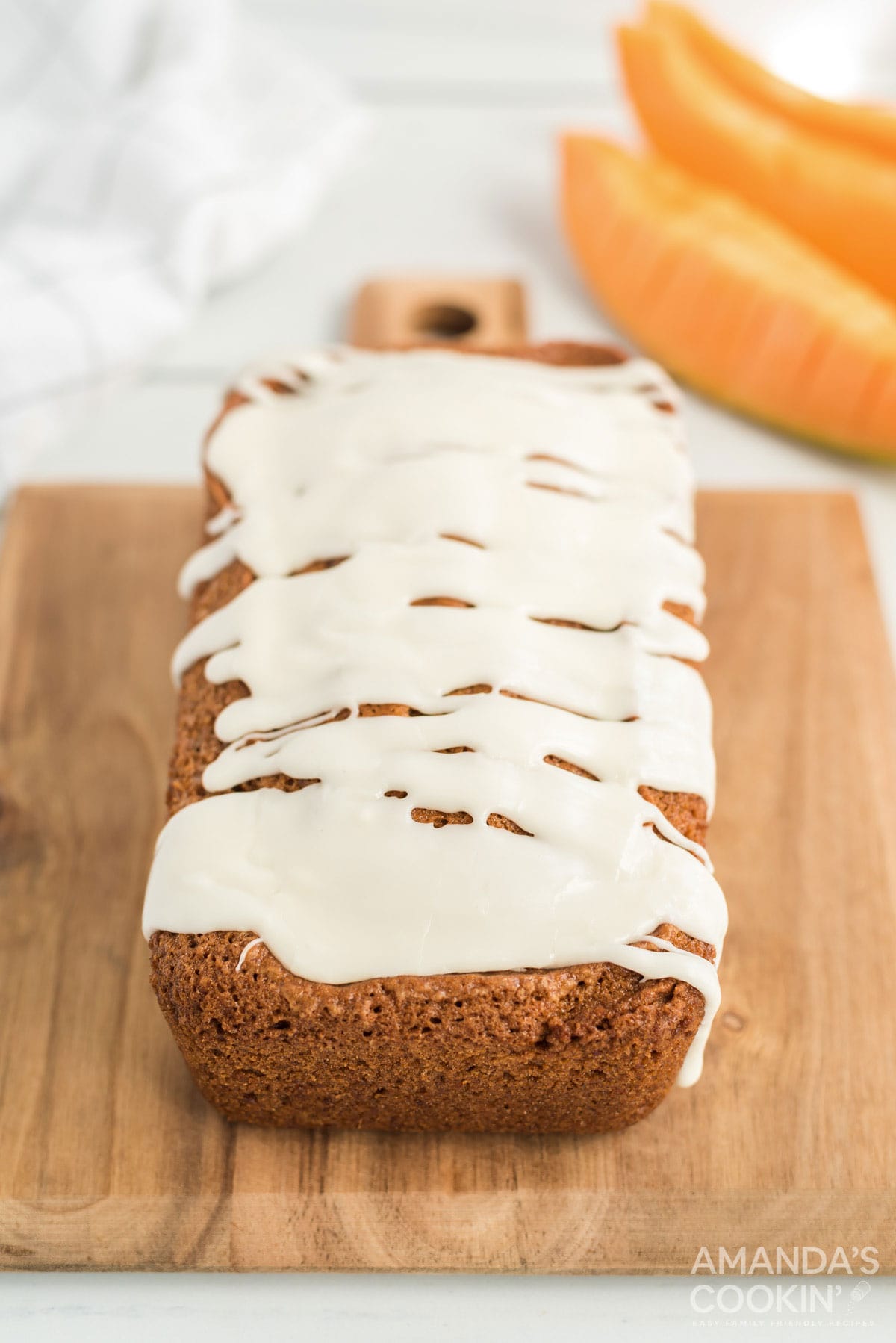 loaf of iced quick bread on cutting board