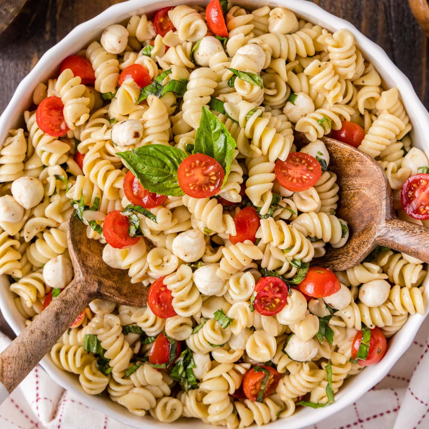 Close up photo of Caprese Pasta Salad in a bowl with two spoons