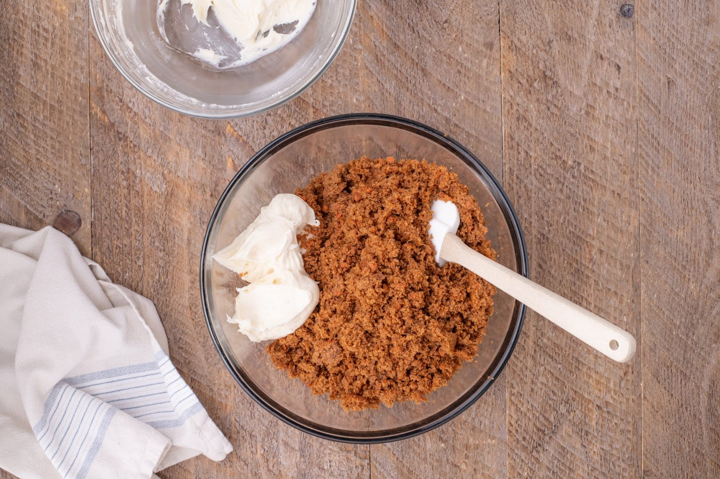 combining cream cheese frosting with crumbled carrot cake