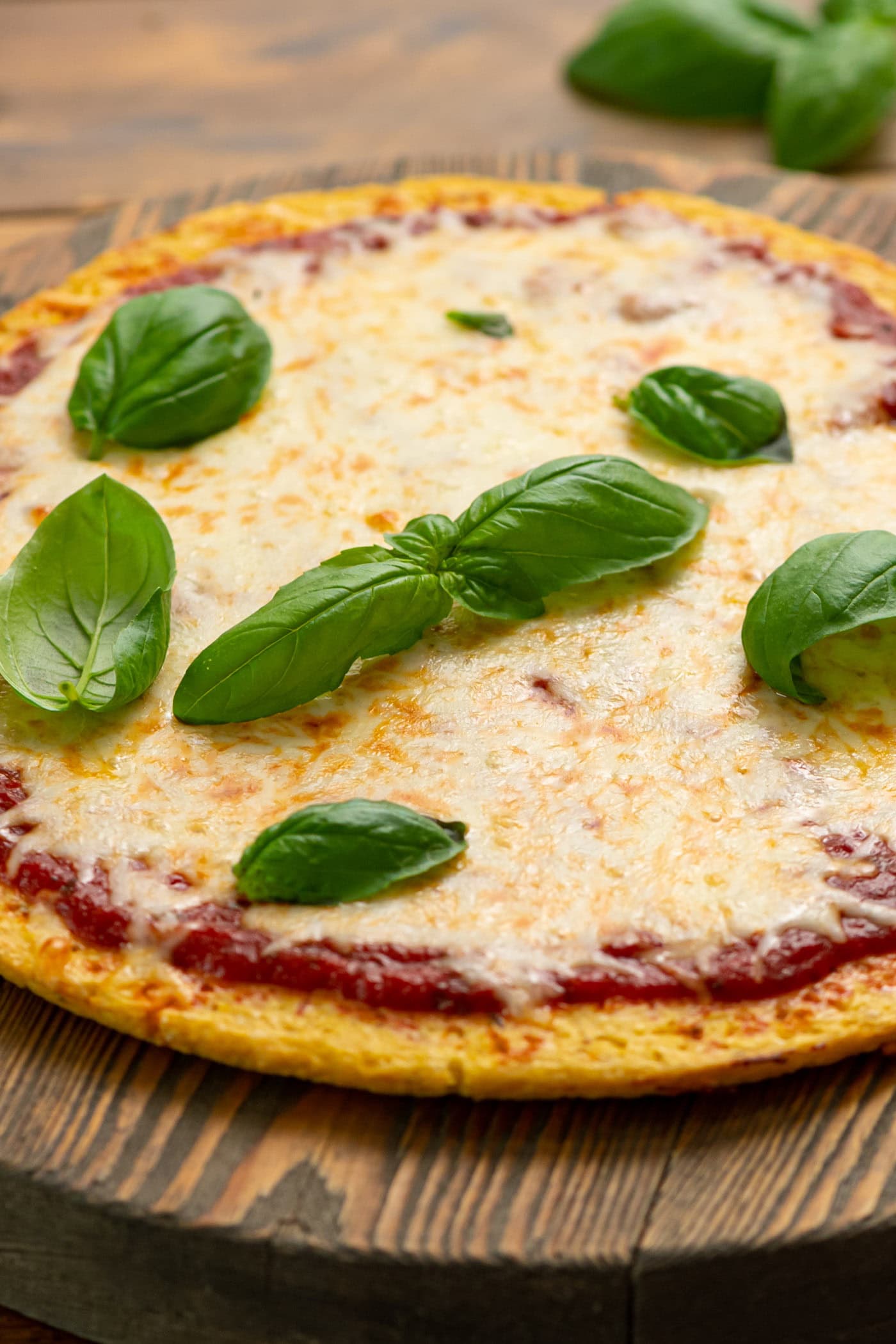 Cauliflower Pizza Crust pizza topped with basil leaves