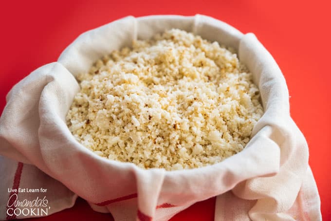 Grated cauliflower in a cheesecloth lined bowl