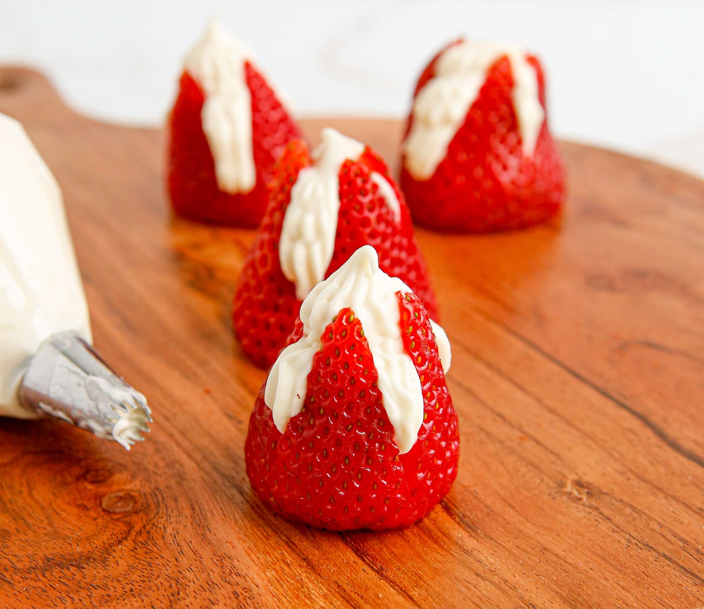piping cheesecake into strawberries