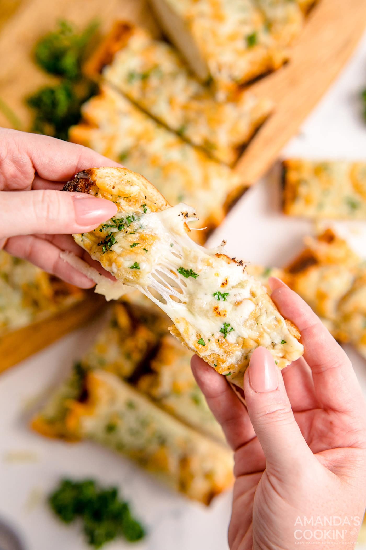 pulling a piece of Cheesy Garlic Bread apart