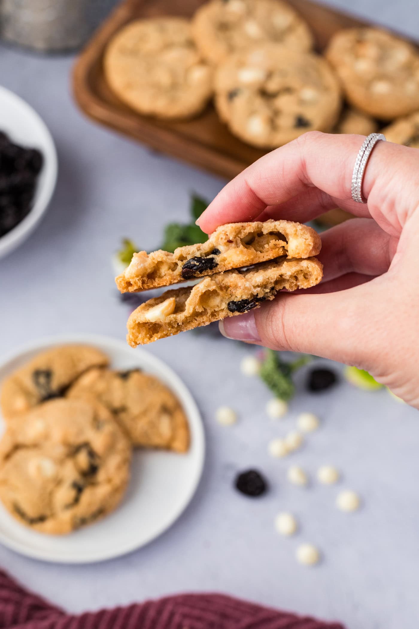Hand holding a Cherry White Chocolate Chip Cookie broken in half