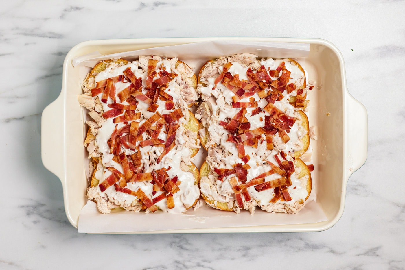 Chopped bacon sprinkled on top of ranch and chicken over slider buns