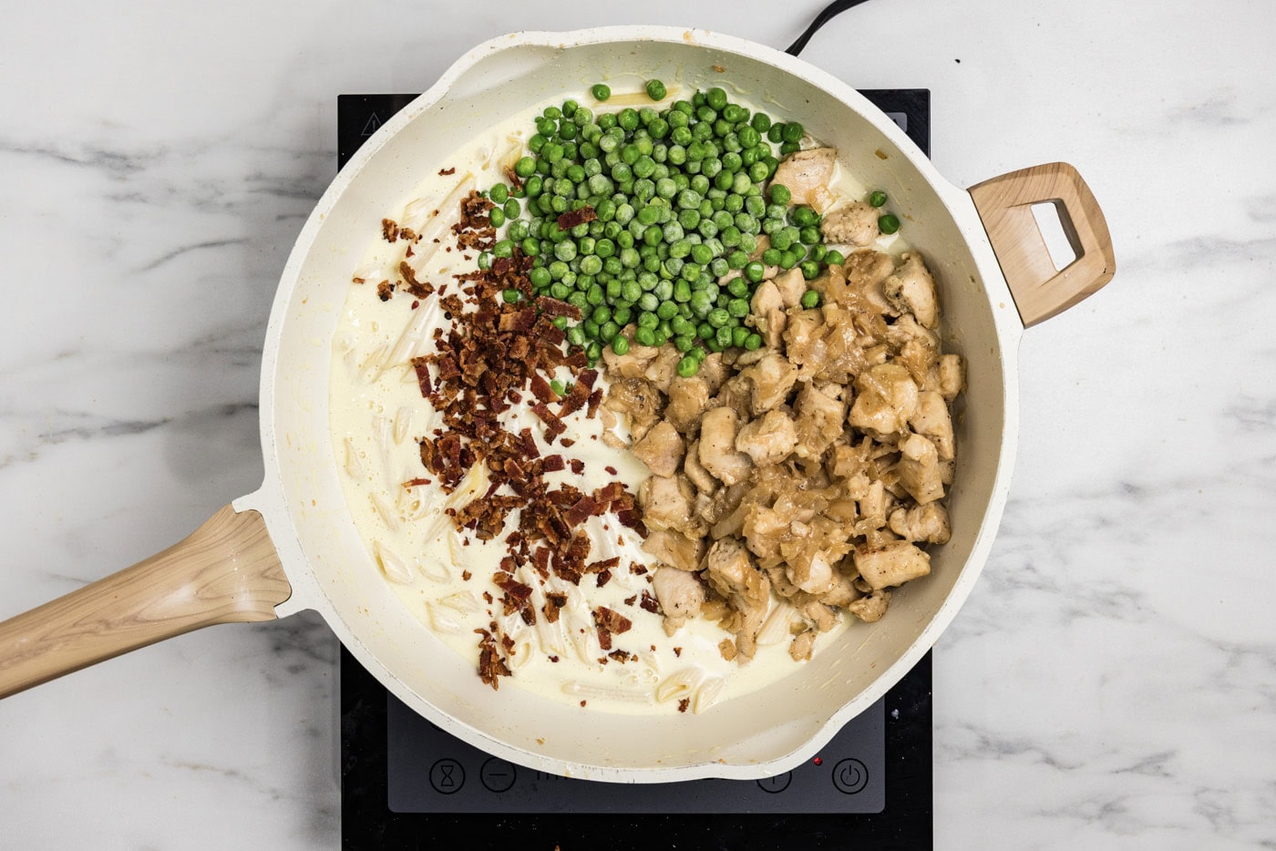peas, crumbled bacon, and chicken added to skillet with pasta and cream sauce
