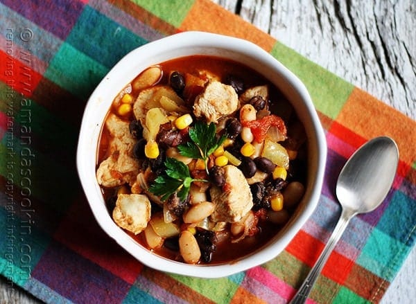 An overhead photo of a bowl of chicken chili with black beans and corn and a spoon on the side.