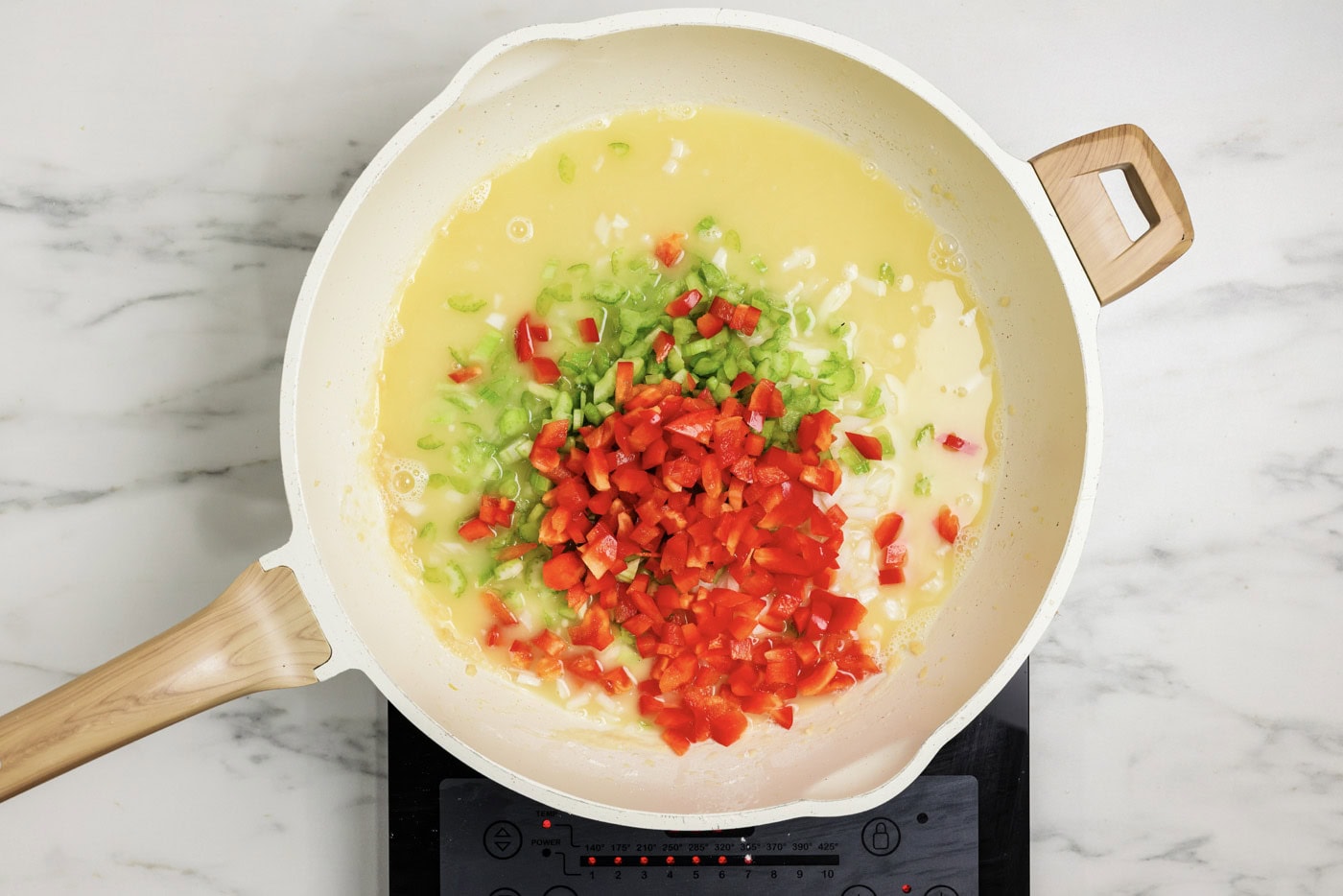 Onion, celery, and bell pepper added to roux in a skillet