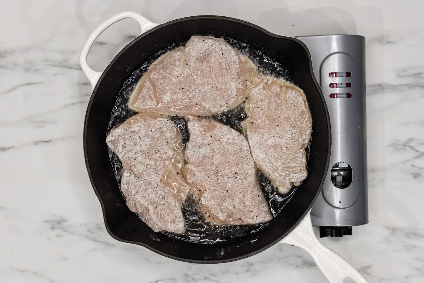 lightly coated chicken cutlets in a cast iron skillet