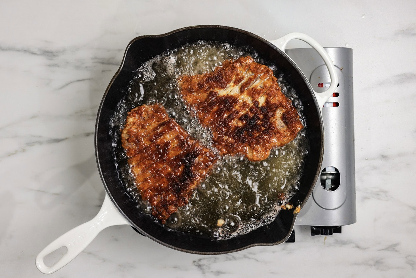 Chicken fried steak cooking in oil in a skillet
