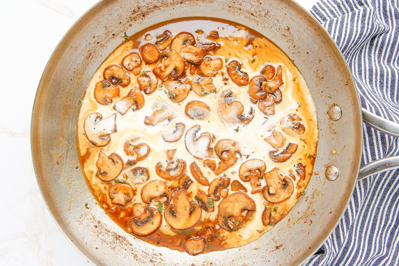 heavy cream and wine added to mushrooms in a skillet