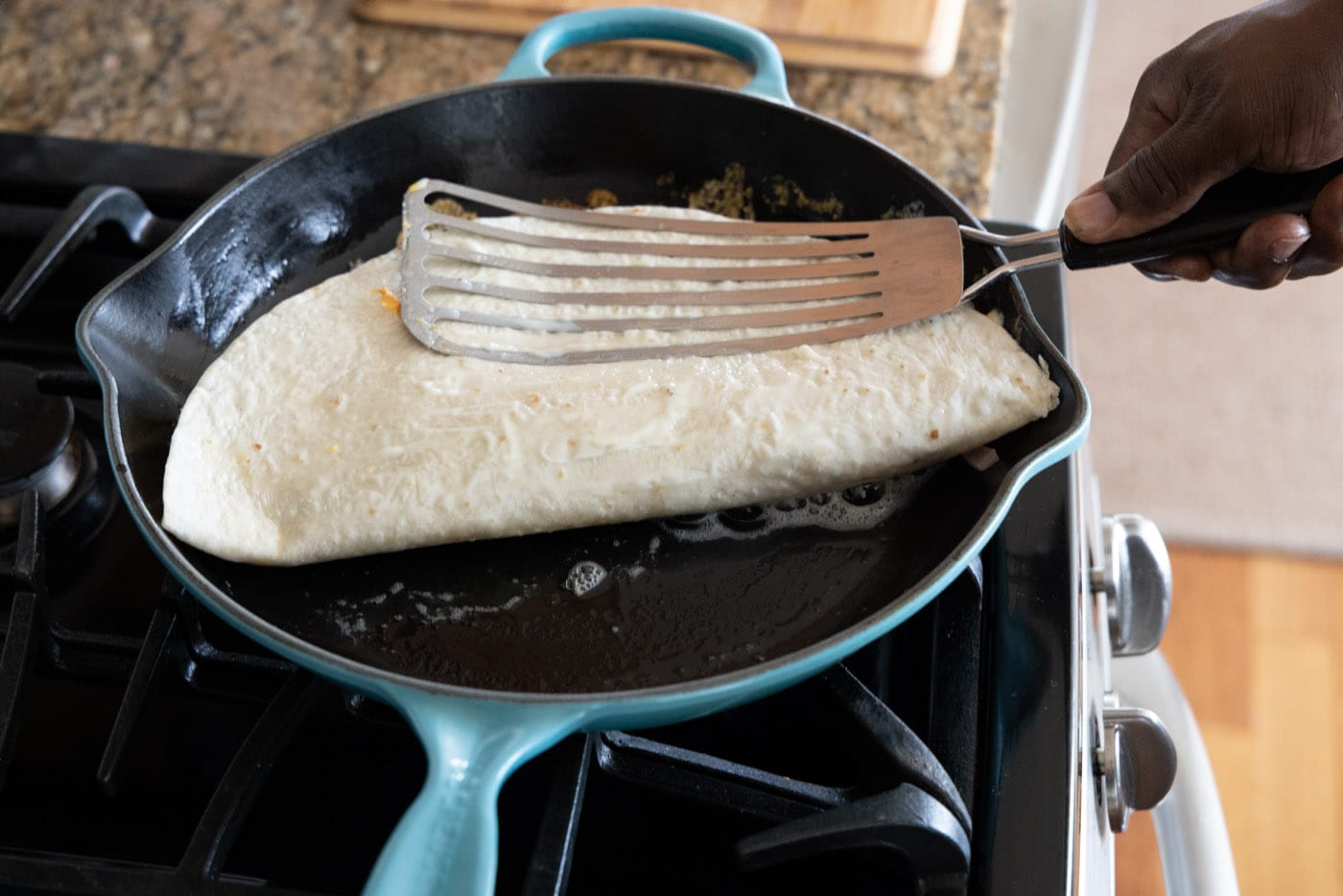 pressing chicken quesadilla into skillet