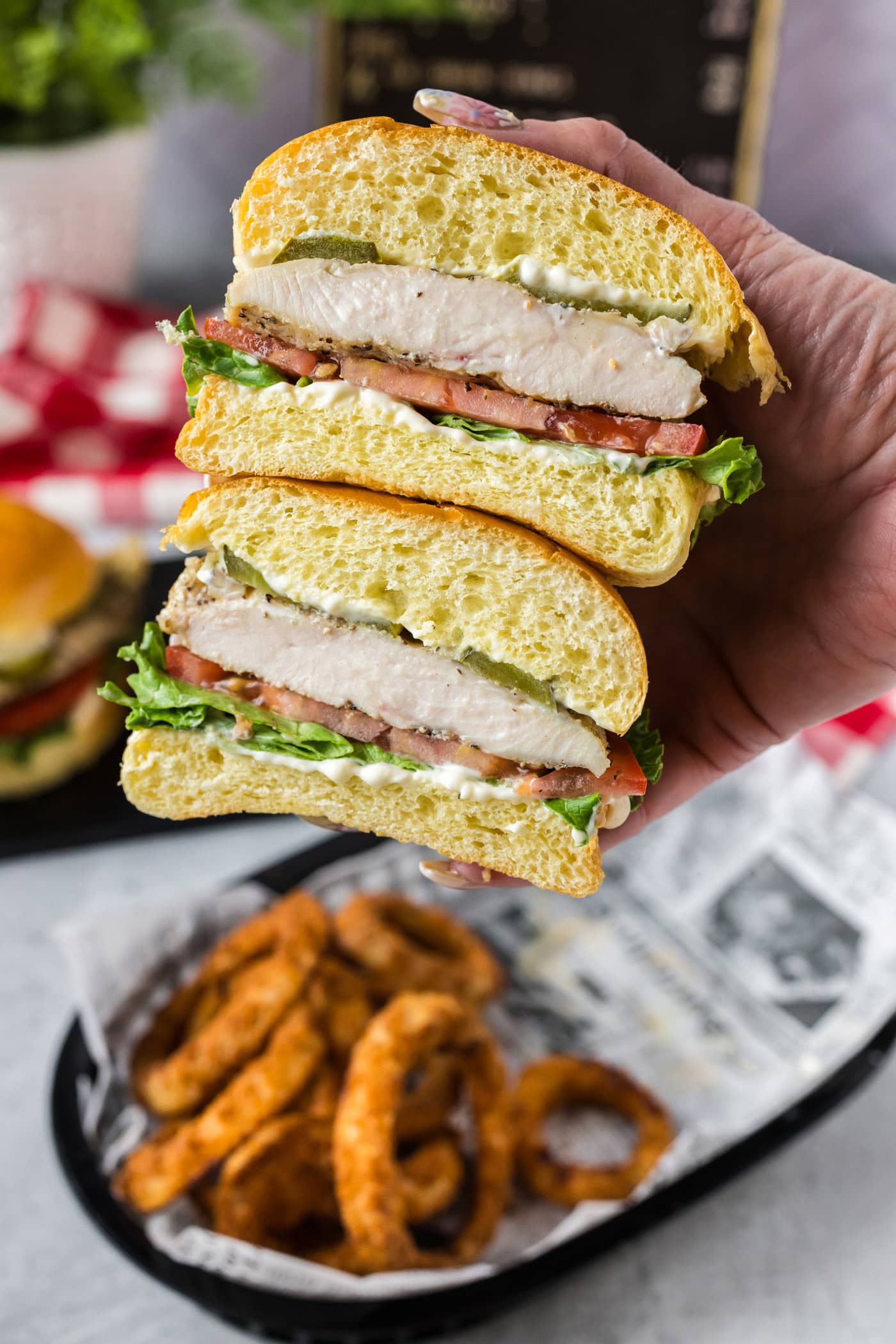 Hand holding a Chicken Sandwich that has been cut in half