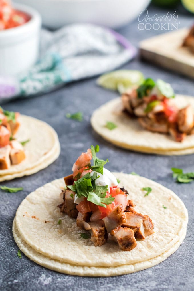 chicken taco ingredients piled in three corn tortillas
