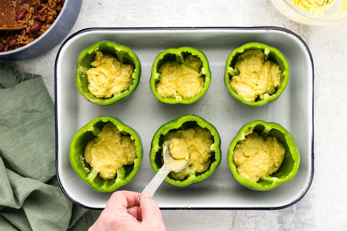 spooning cornbread batter into hollowed out bell peppers