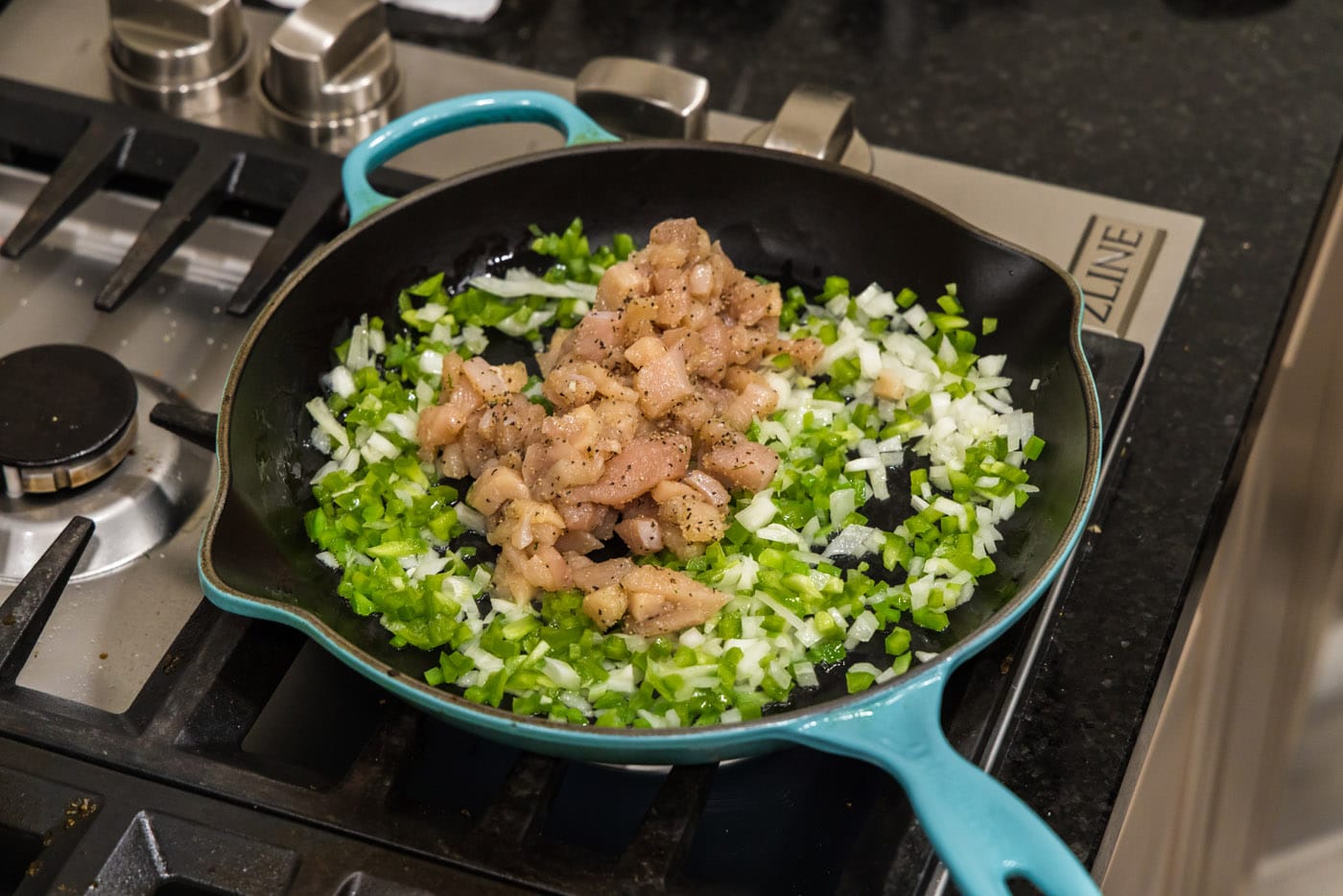 adding cubed chicken to skillet with veggies