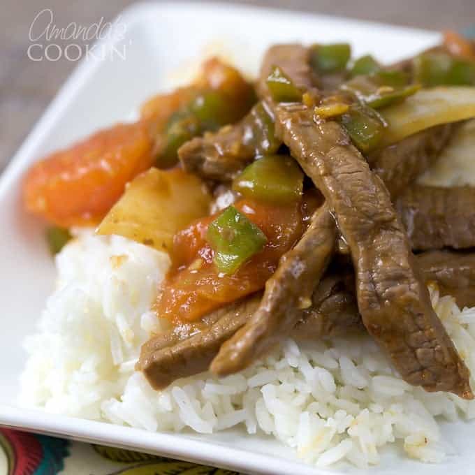 A close up of a white plate with white rice and Chinese pepper steak on top.