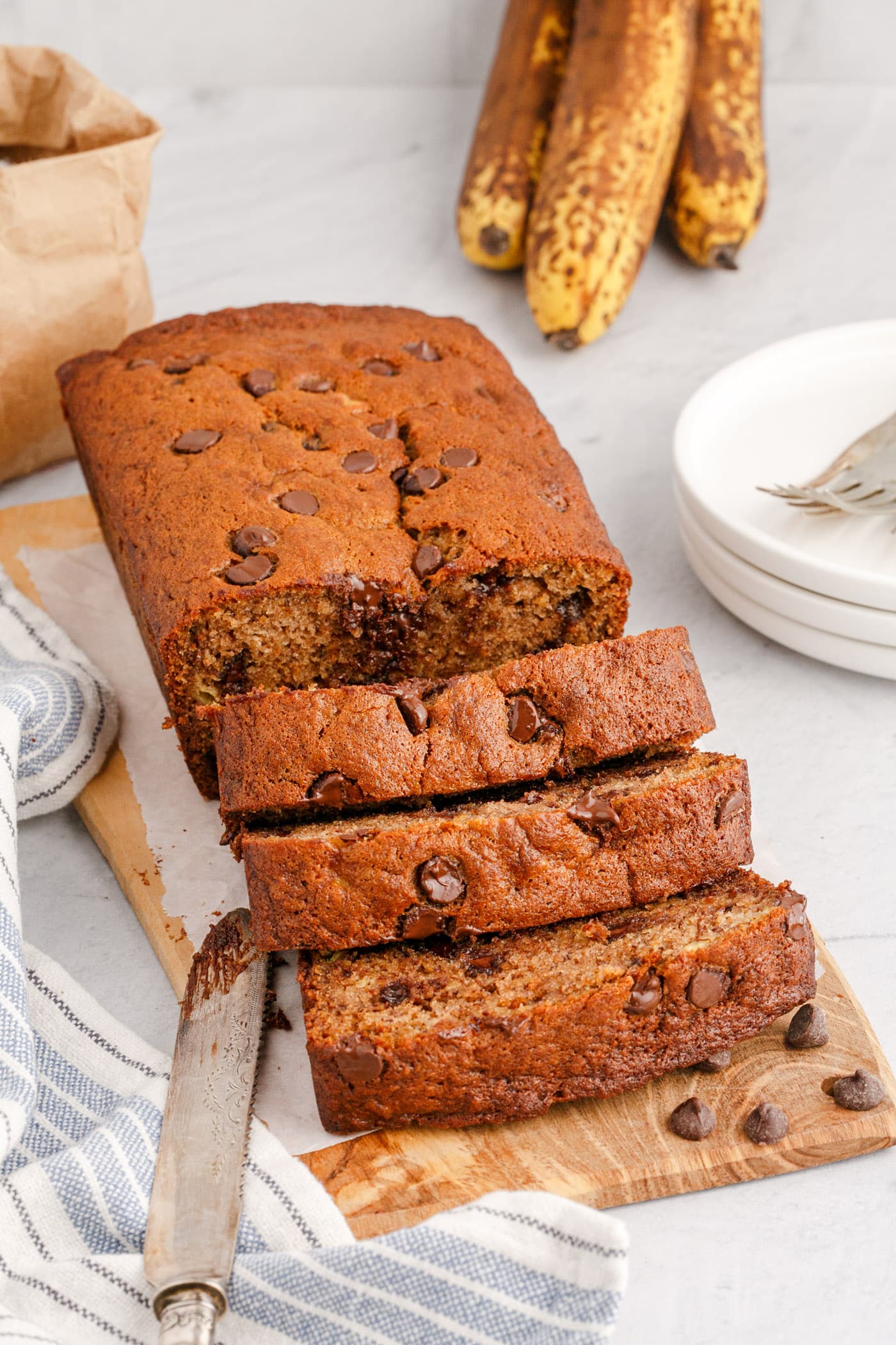 Loaf of Chocolate Chip Banana Bread sliced on a wooden cutting board