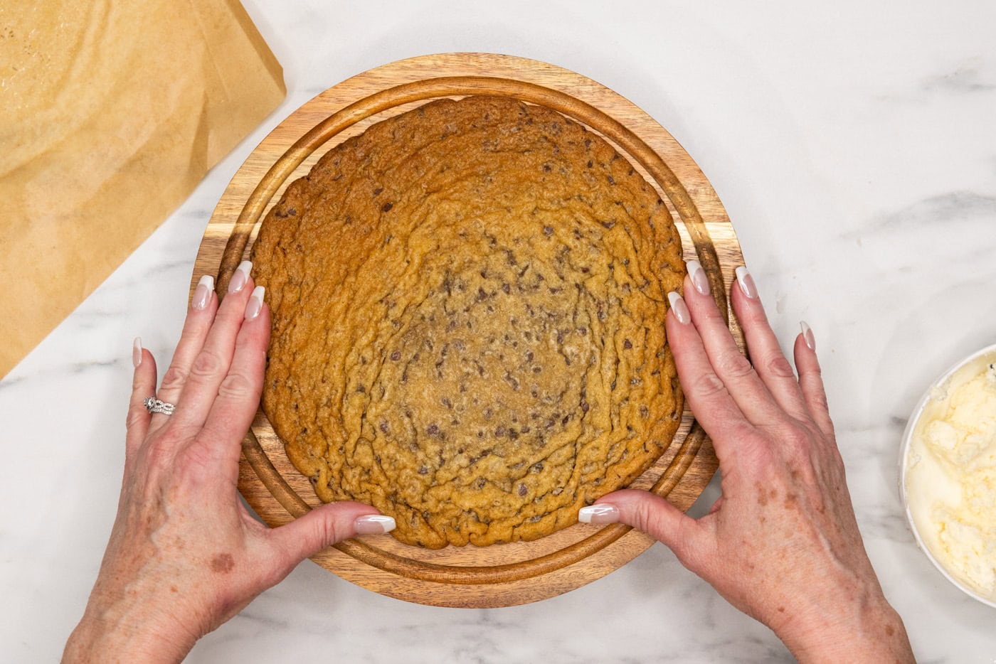 placing jumbo chocolate chip cookie onto cake stand