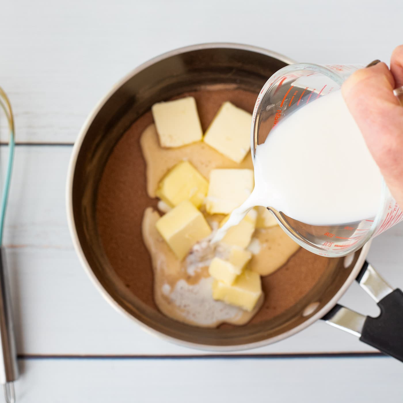 pouring milk into saucepan with butter and cocoa powder