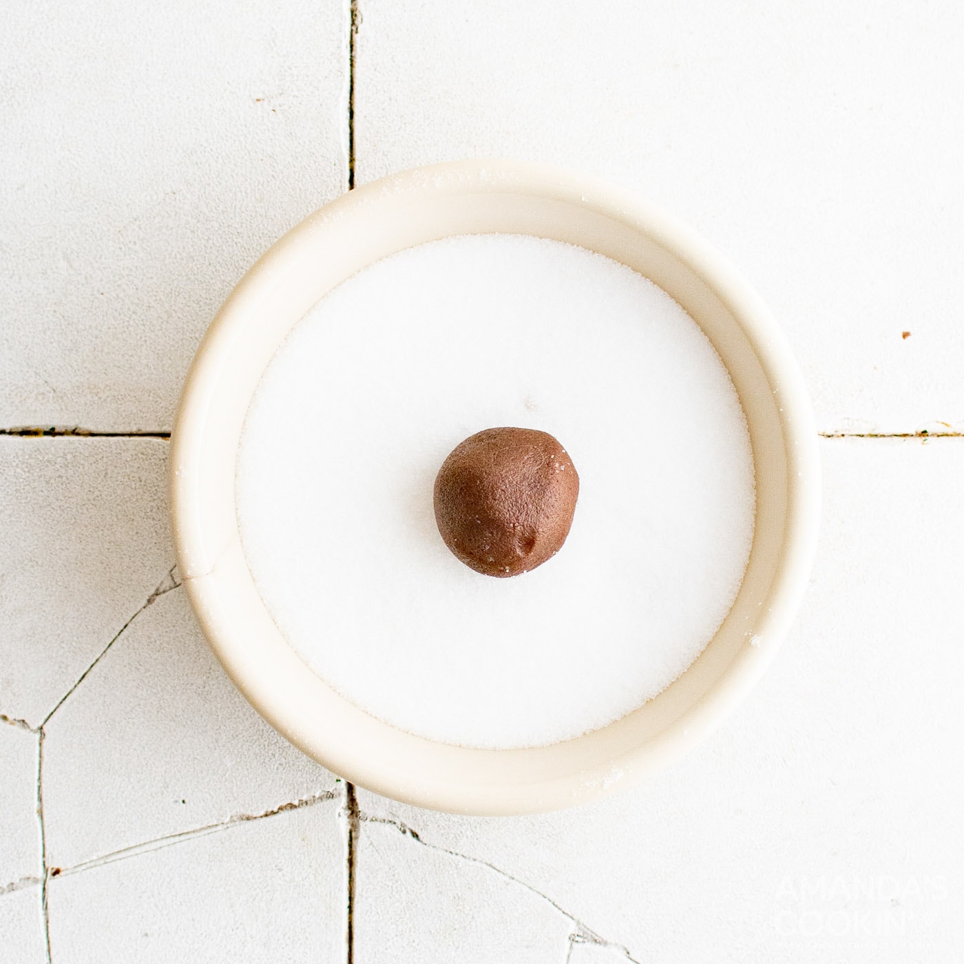 chocolate cookie dough ball in a bowl of sugar