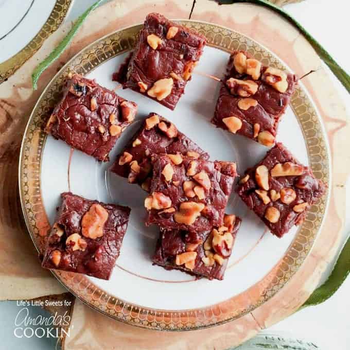 An overhead of chocolate walnut fudge squares on a white and gold plate.