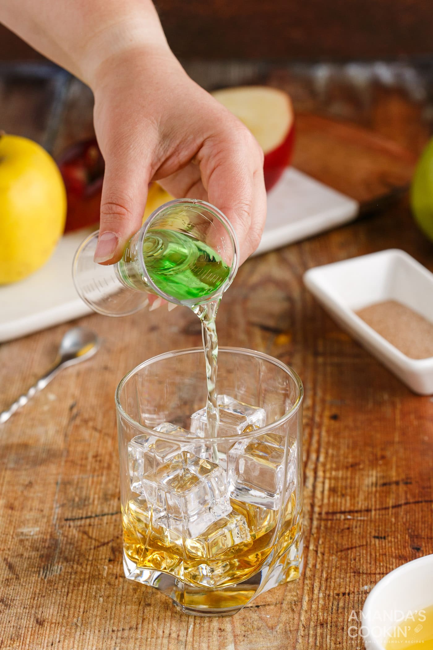 pouring apple pucker into a rock glass