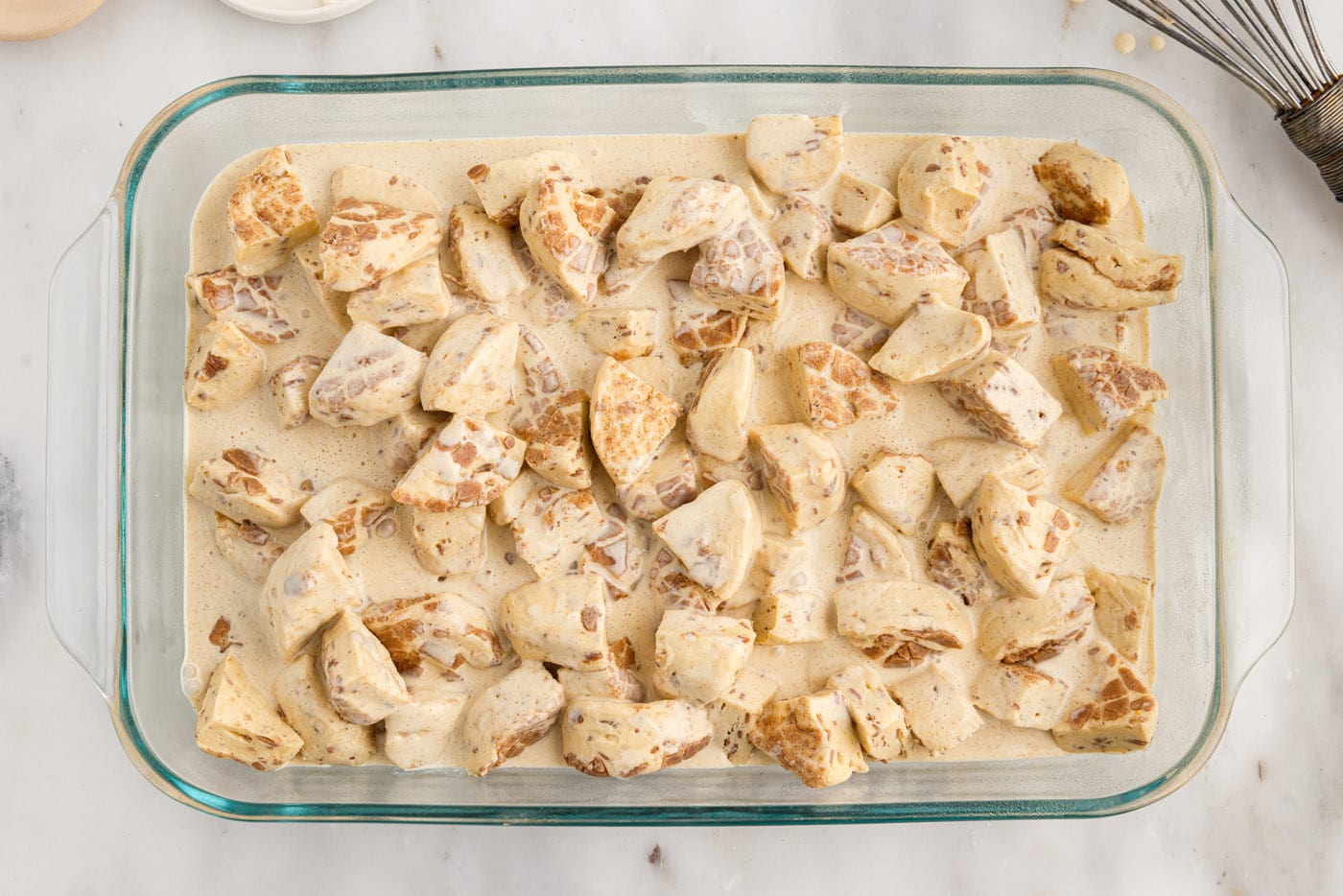cream mixture poured over chopped cinnamon rolls in a baking dish