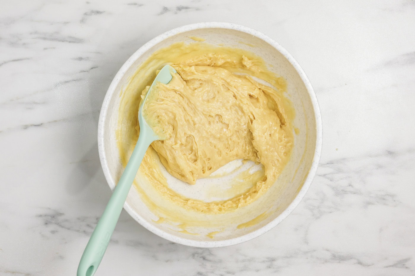 Rubber spatula in a bowl with vanilla muffin batter