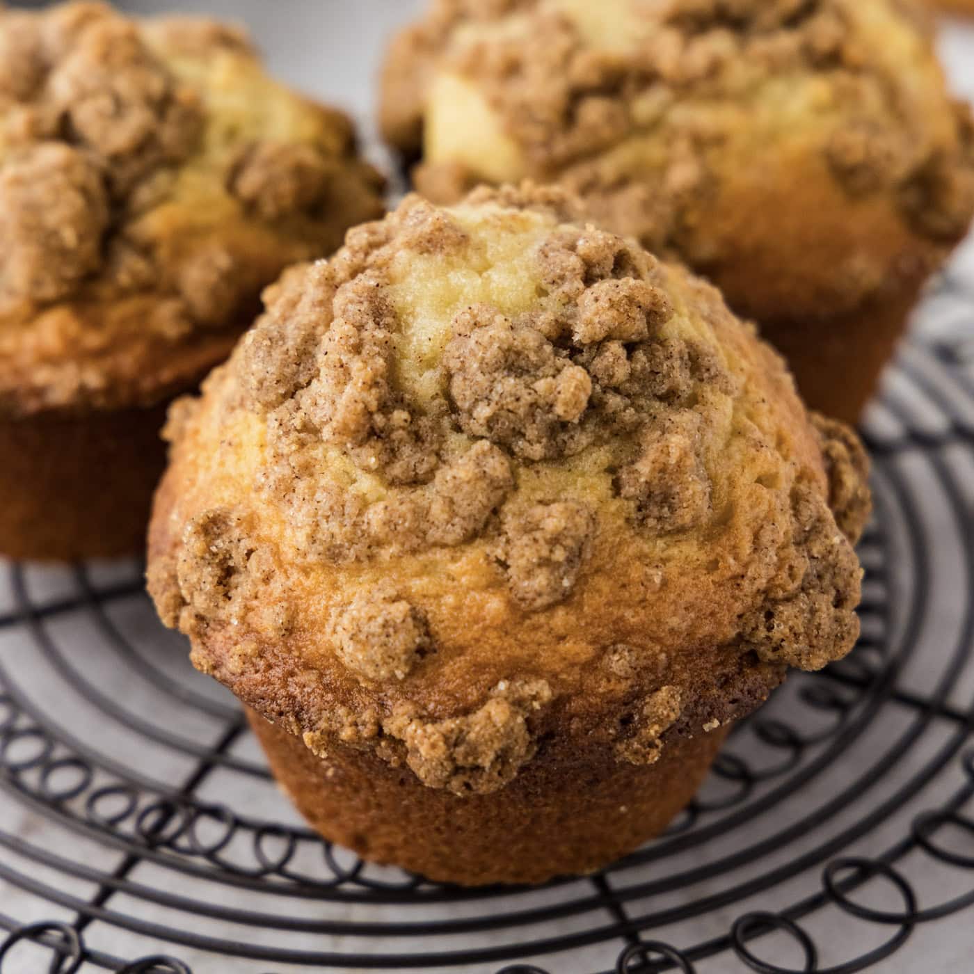 A close up of a cinnamon streusel muffin on a wire rack