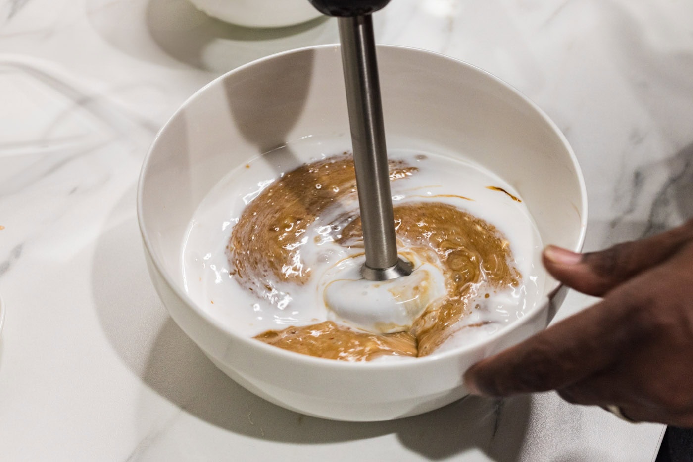 blitzing coconut sauce ingredients with an immersion blender