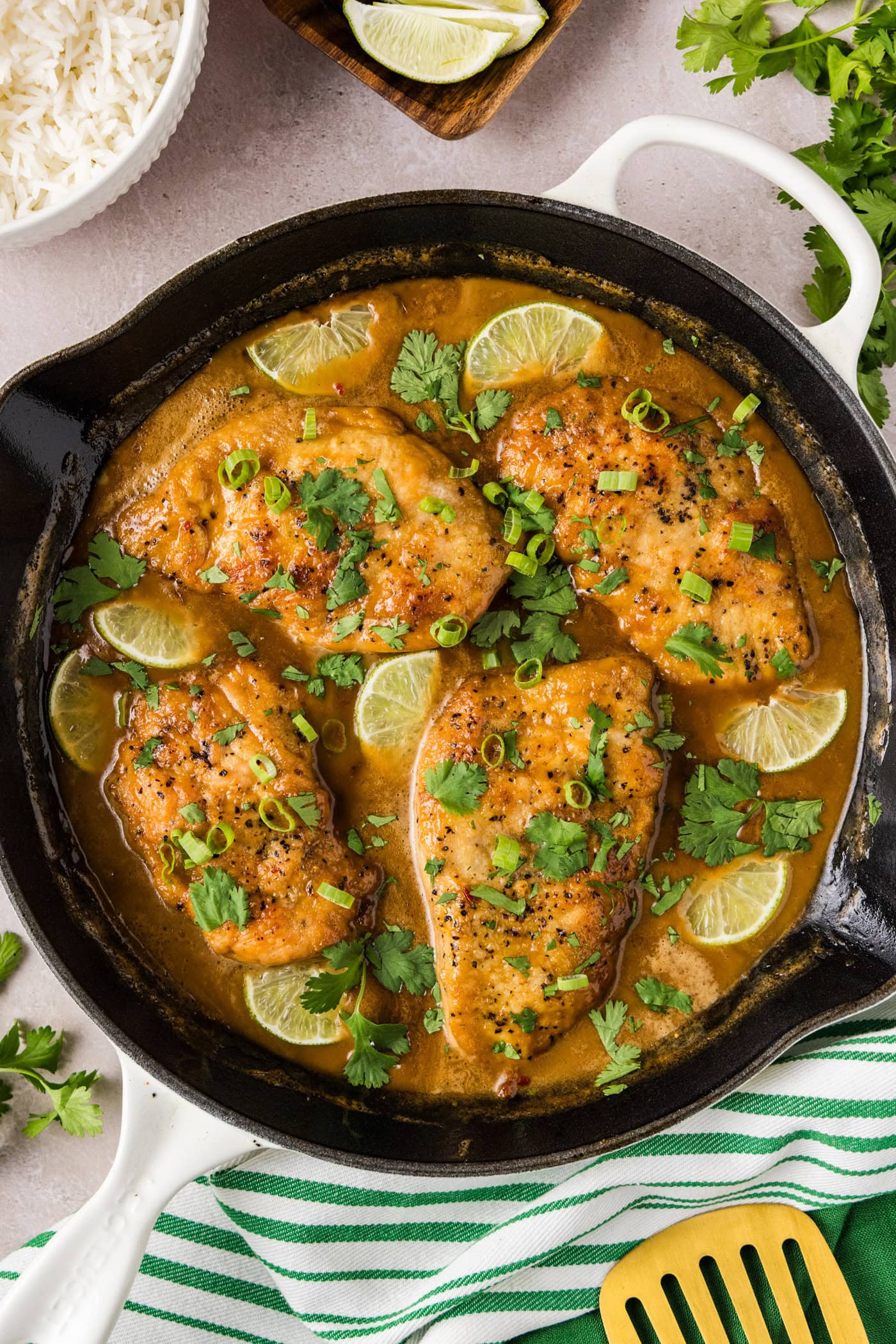 Skillet of Coconut Chicken topped with limes and green onion