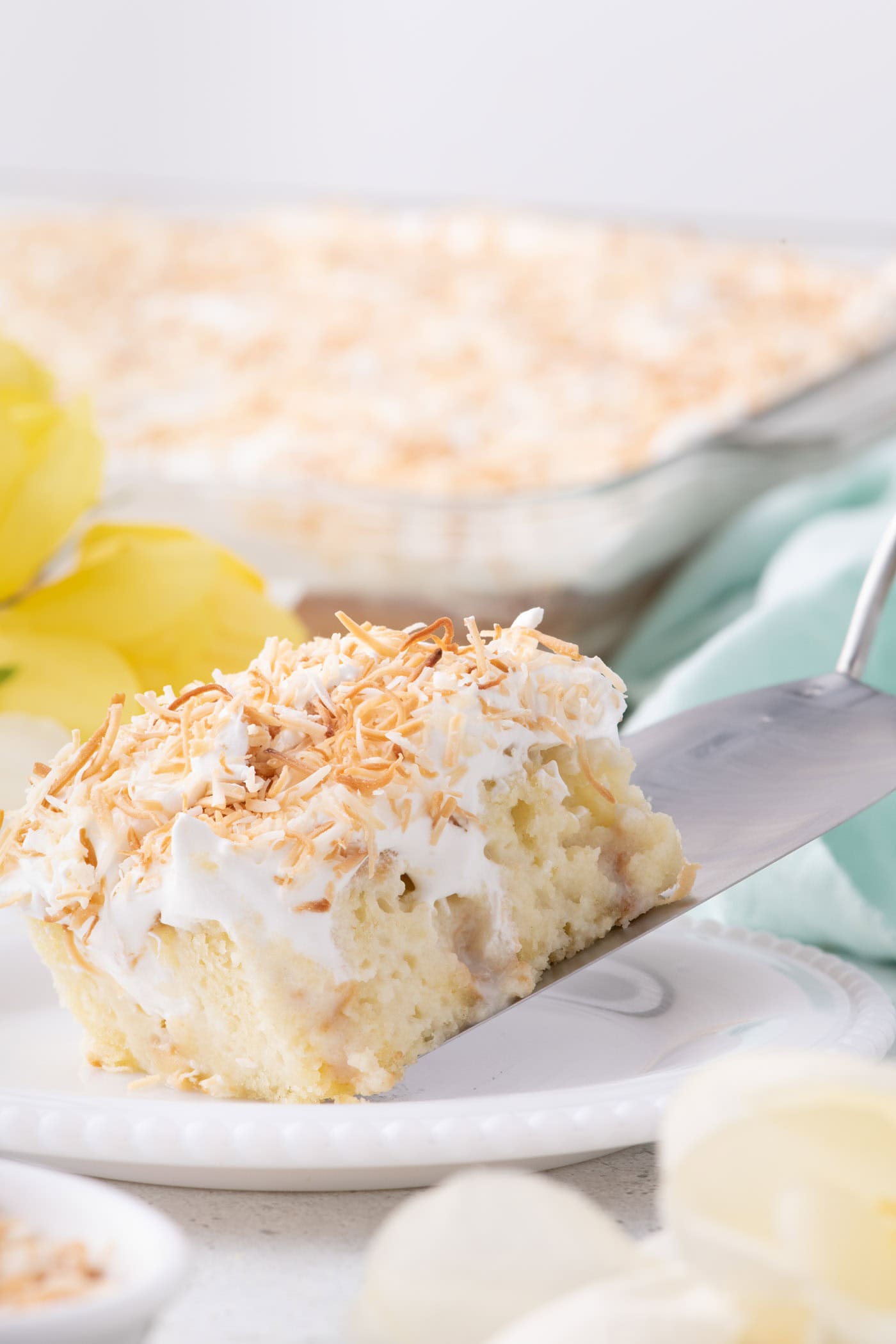 Slice of Coconut Poke Cake being served onto a plate