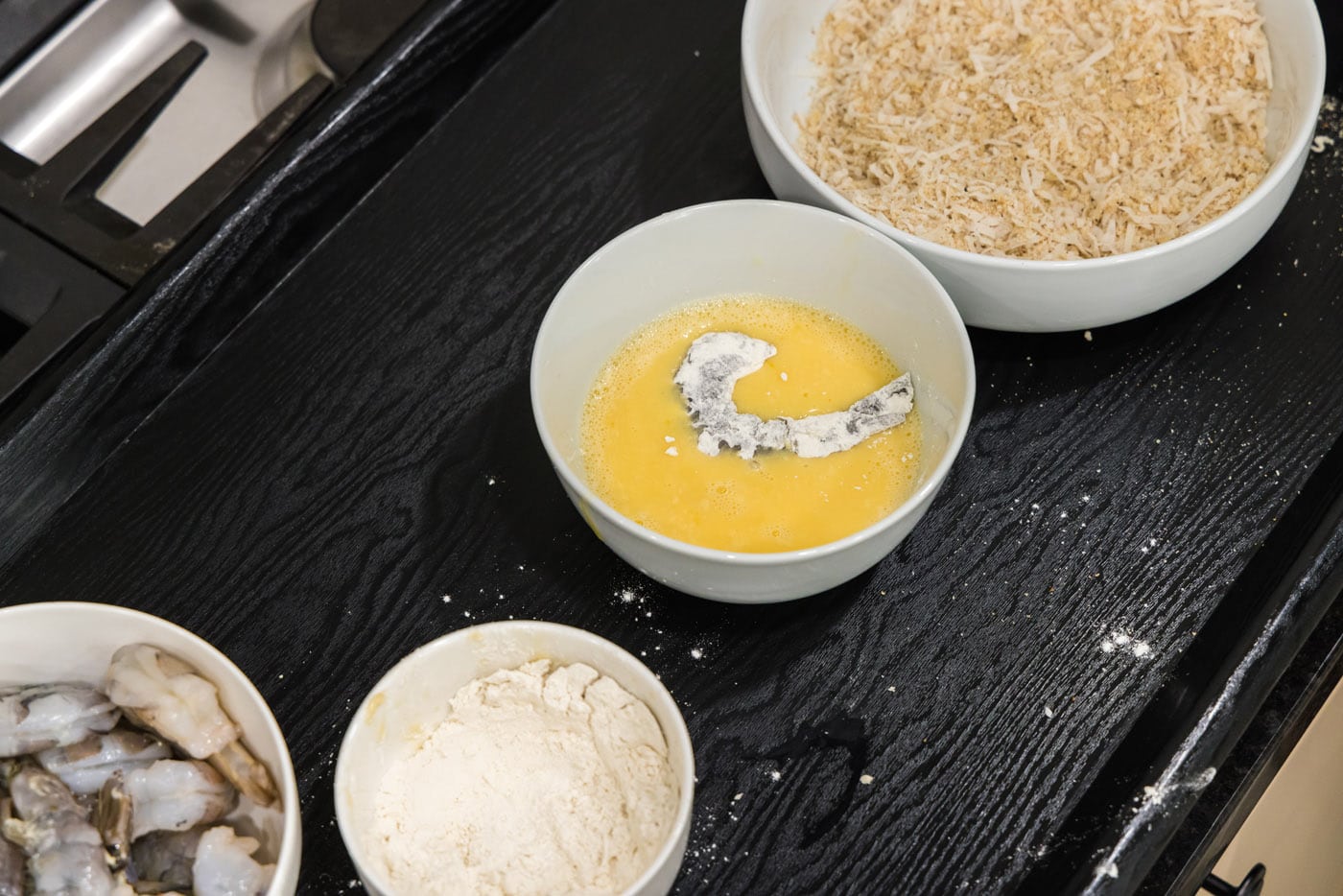 dipping floured shrimp into egg