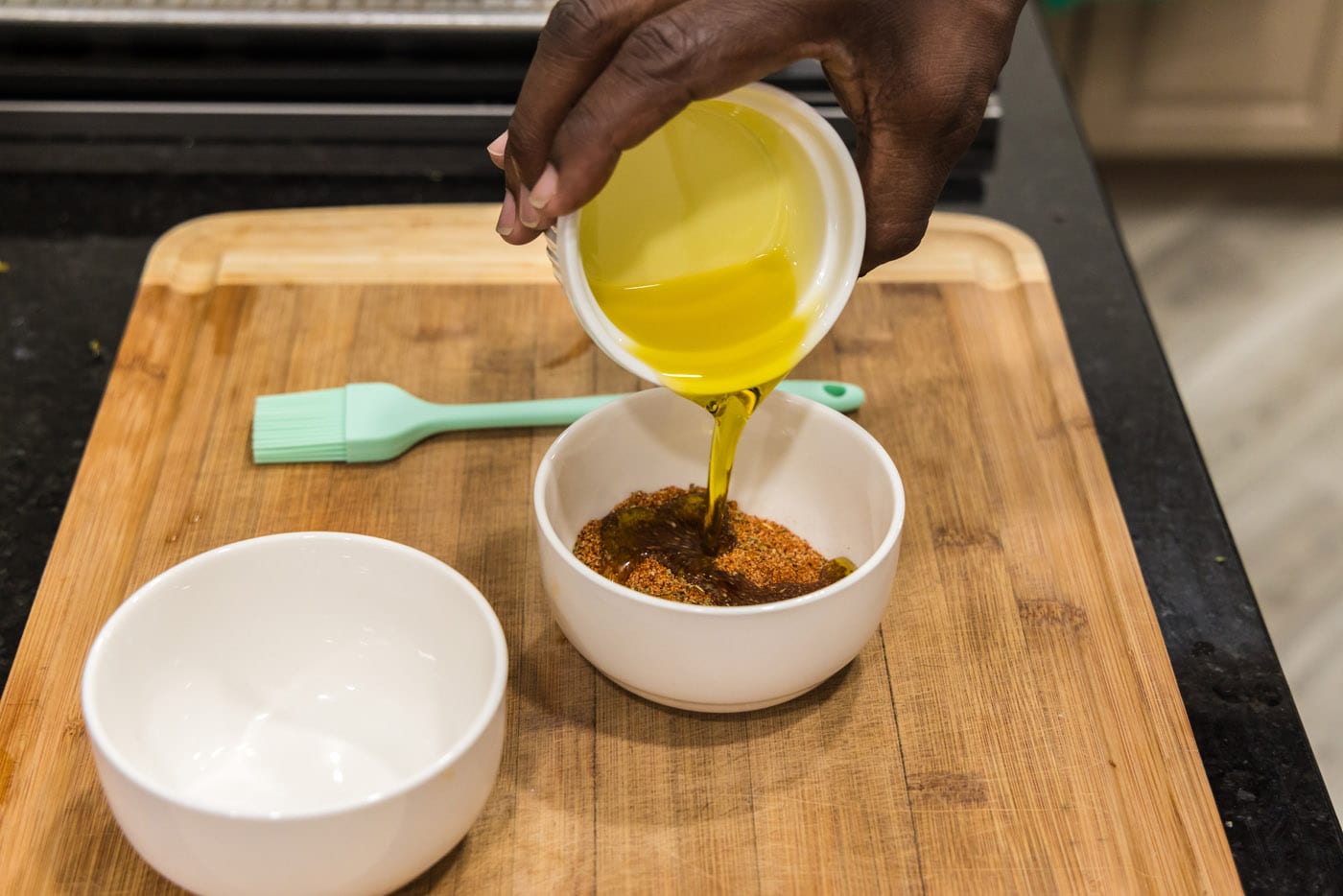 pouring olive oil into shrimp seasoning