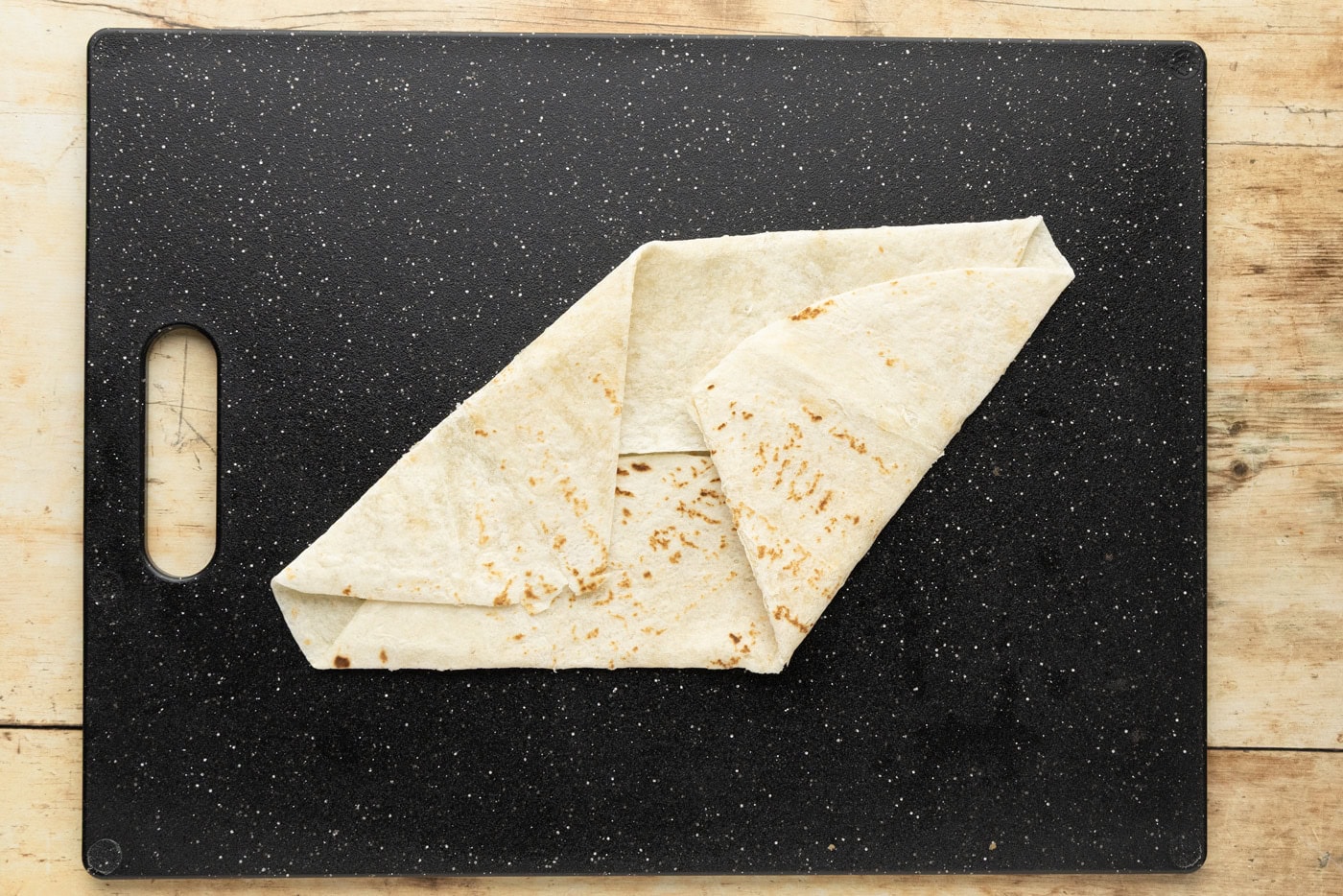 Third fold laid alongside the previous one, the tortilla starting to take on straight angled edges