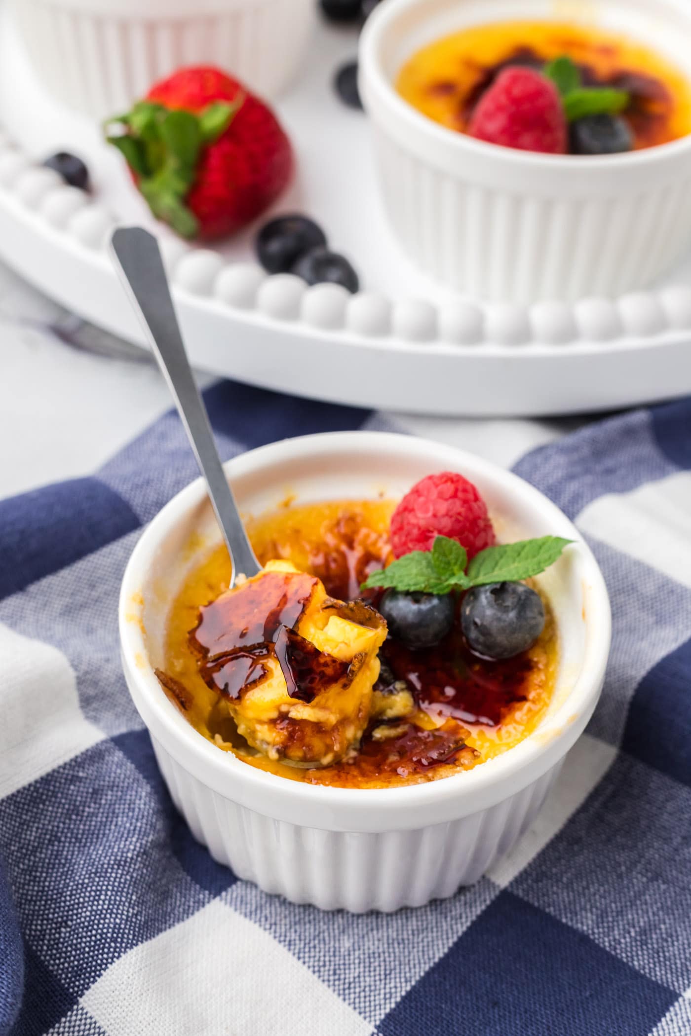Spoonful of Creme Brulee sitting in a ramekin of Creme Brulee