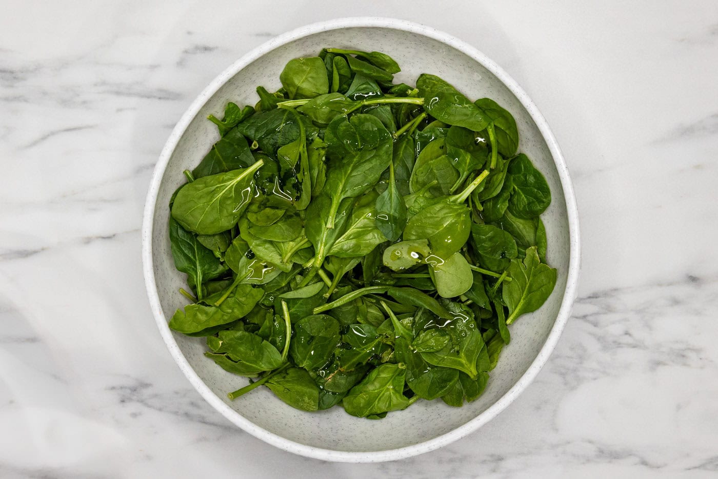spinach in a bowl tossed with oil