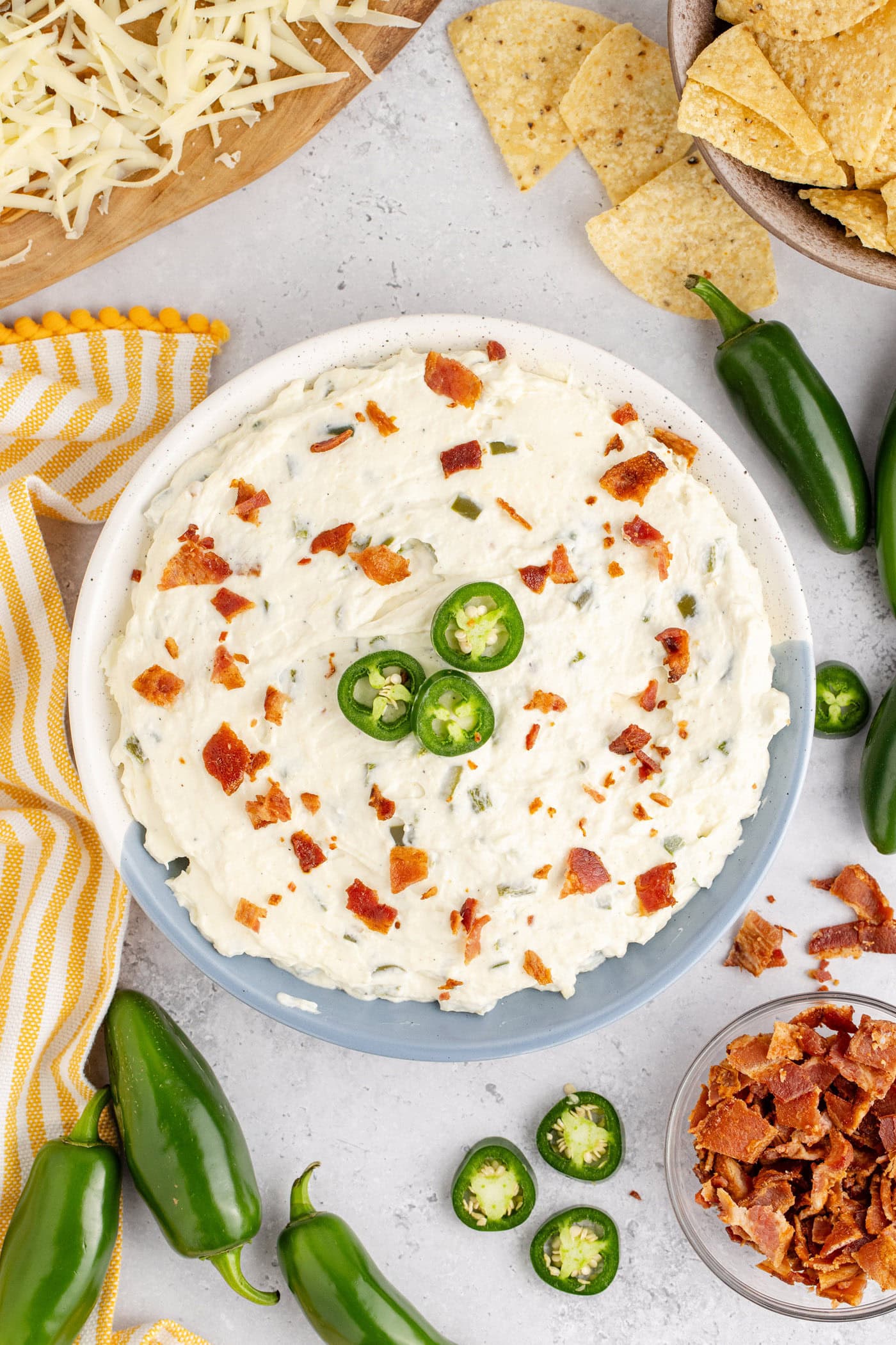 Bowl of Crockpot Jalapeno Popper Dip topped with sliced jalapeno and bacon pieces