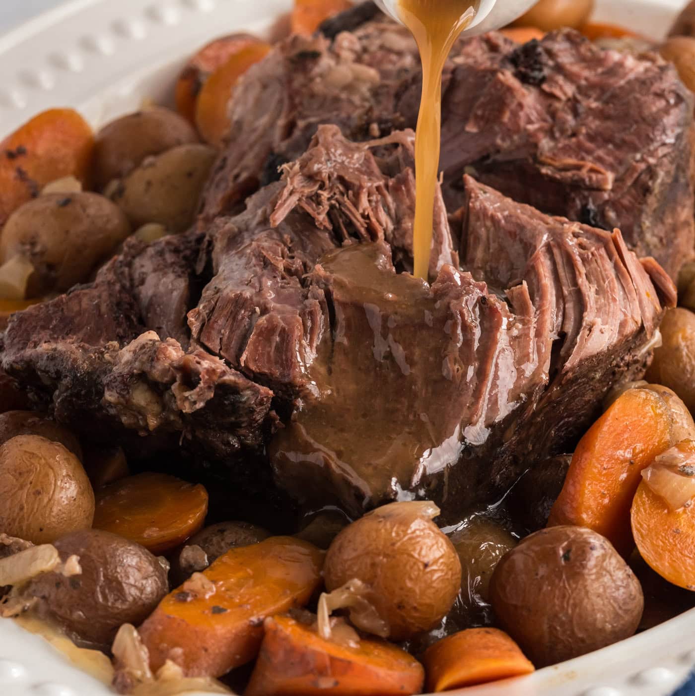 gracy pouring on crockpot roast beef on a platter