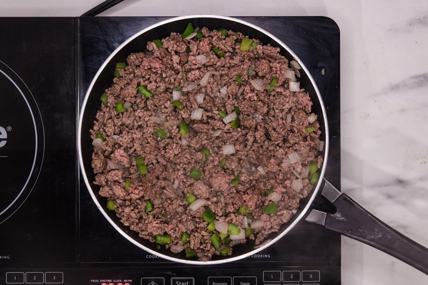 browned ground beef with onion and bell pepper in a skillet