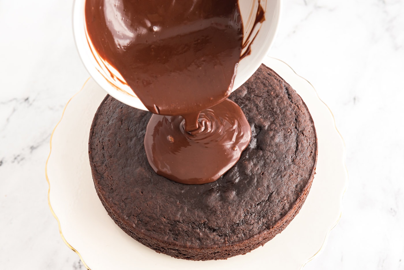 pouring ganache over chocolate cake