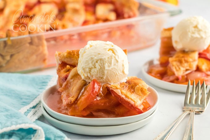 peach pie on plate topped with vanilla ice cream