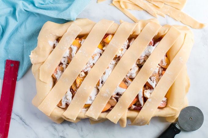 strips of pie dough spread across top of pie in pan