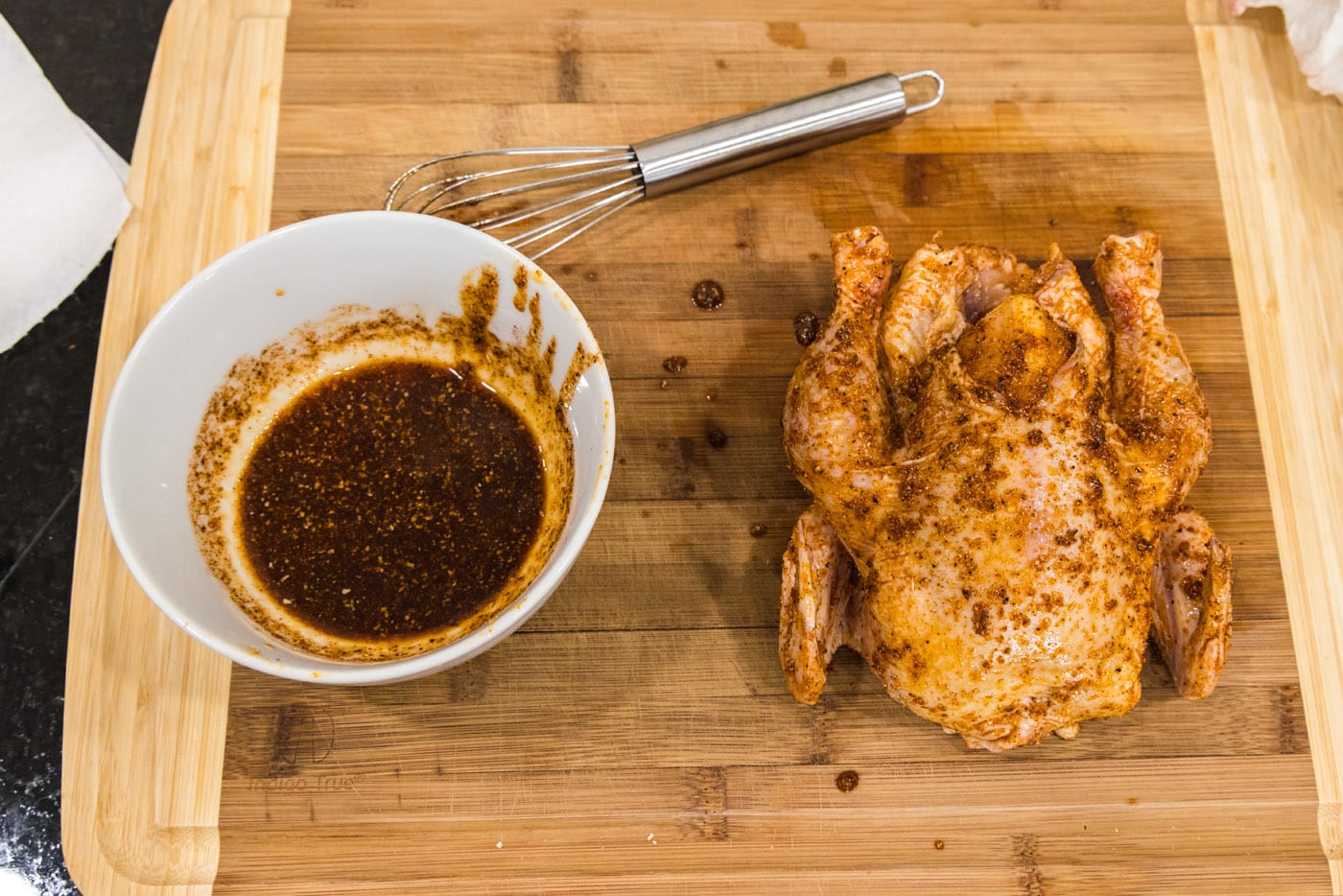 adding wet rub to cornish hen on a cutting board