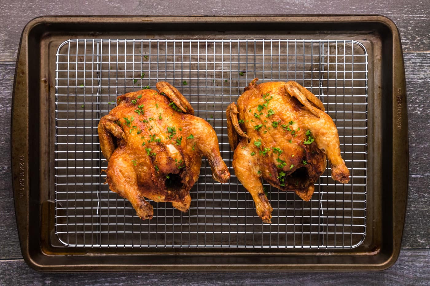 golden skinned deep fried cornish hens on a wire cooling rack