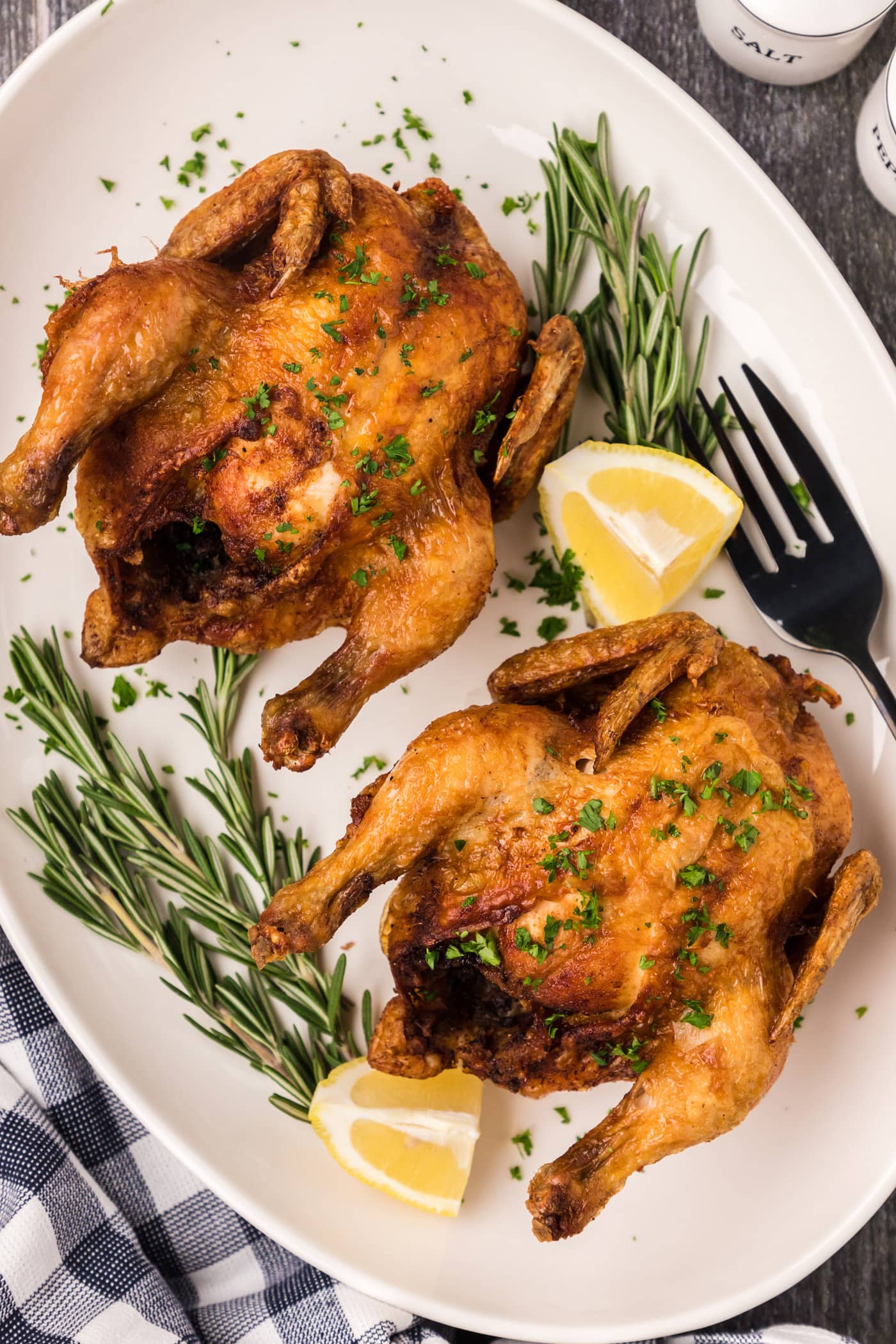 Deep Fried Cornish Hens on a platter with lemons and herbs