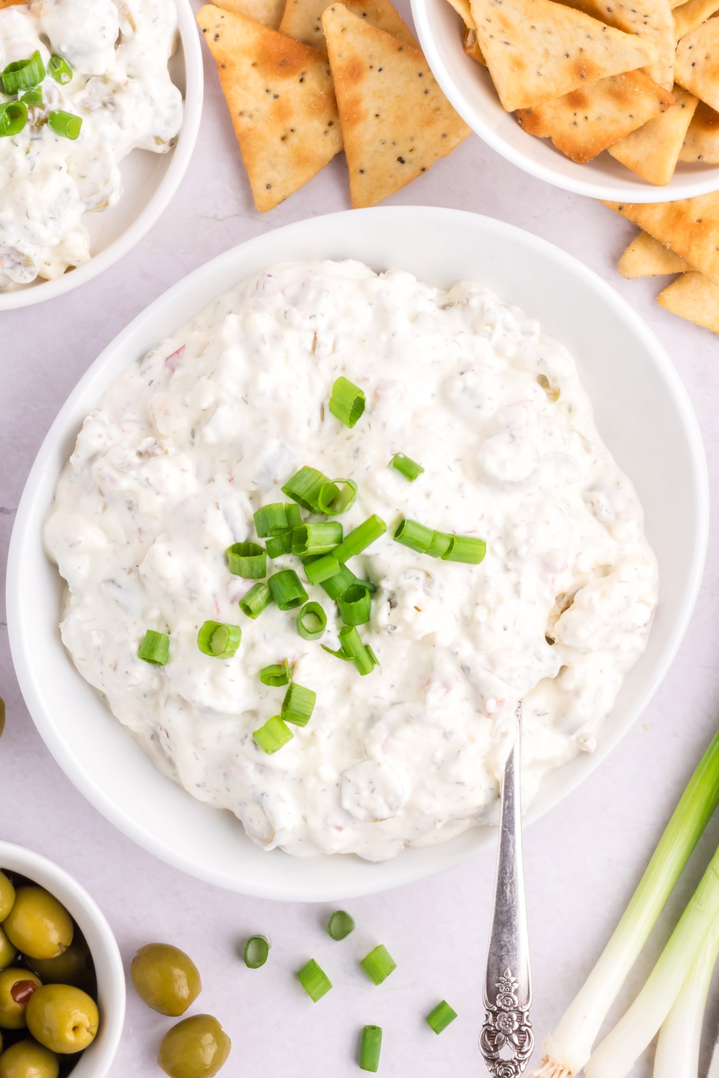 Bowl of Dirty Martini Dip with crackers and olives on the side