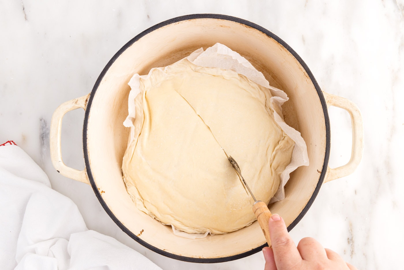 scoring bread dough in a dutch oven